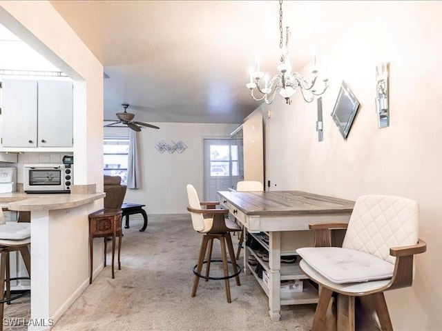 carpeted dining area with ceiling fan with notable chandelier and a wealth of natural light