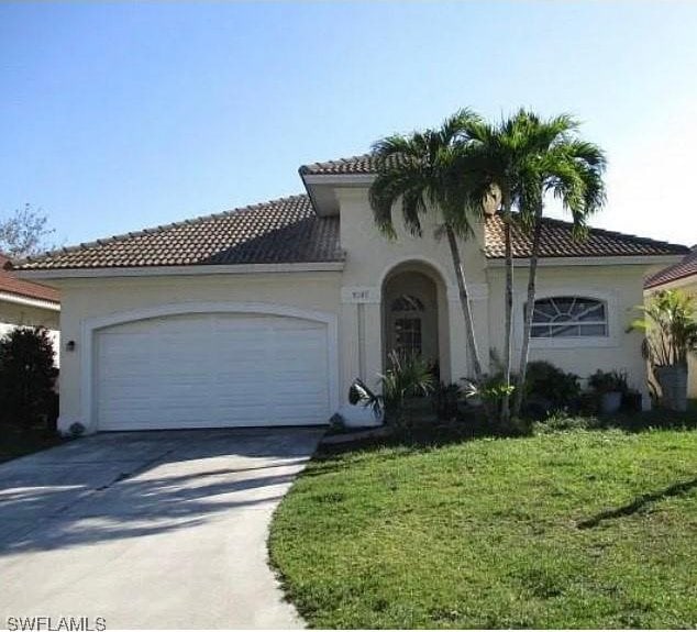 mediterranean / spanish-style house featuring a garage and a front lawn