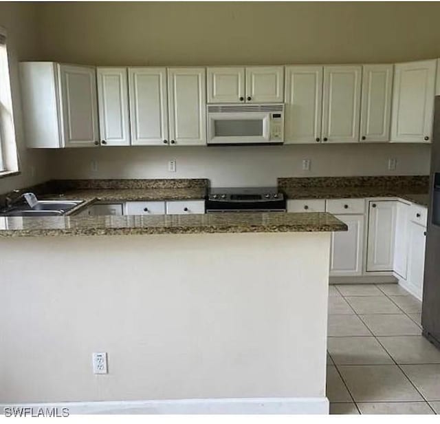 kitchen featuring white cabinetry, range, light tile patterned flooring, and dark stone countertops