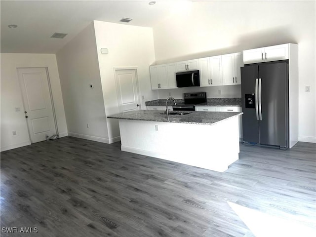 kitchen with white cabinetry, a towering ceiling, range with electric stovetop, an island with sink, and stainless steel fridge with ice dispenser