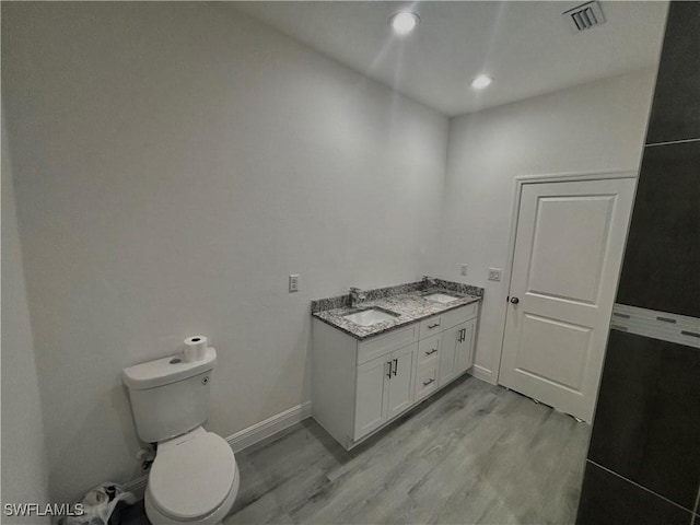 bathroom with wood-type flooring, toilet, and vanity