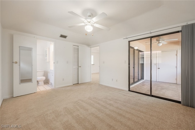 unfurnished bedroom featuring ensuite bath, light colored carpet, and ceiling fan