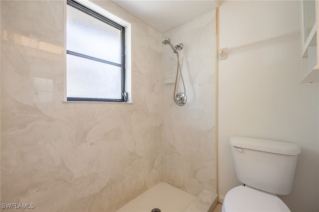 bathroom featuring tiled shower and toilet