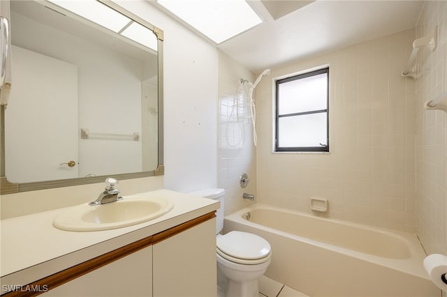 full bathroom featuring tiled shower / bath combo, vanity, a skylight, and toilet