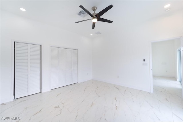 unfurnished bedroom with ceiling fan and two closets