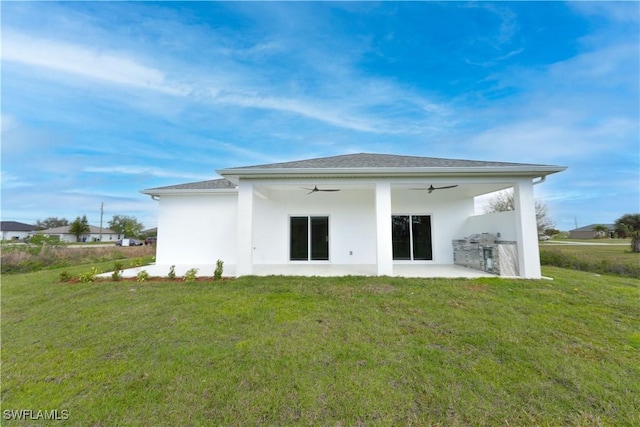 rear view of property with a yard, ceiling fan, and a patio area