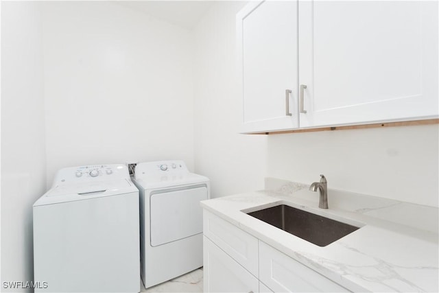 clothes washing area with cabinets, washer and dryer, and sink