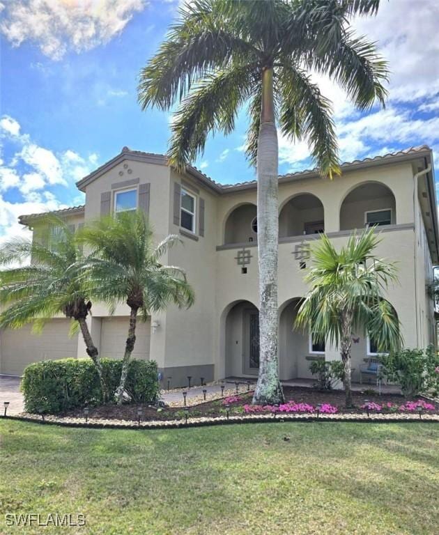 mediterranean / spanish-style house featuring a garage and a front lawn