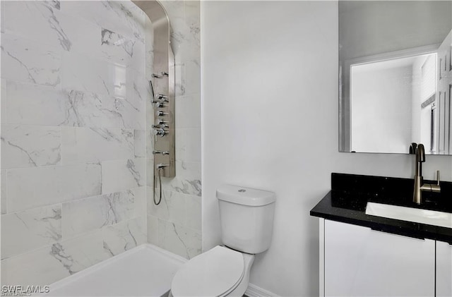 bathroom featuring a tile shower, vanity, and toilet