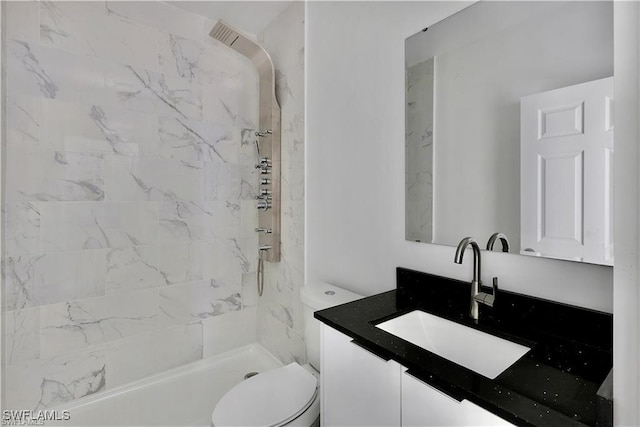 bathroom featuring vanity, tiled shower, and toilet