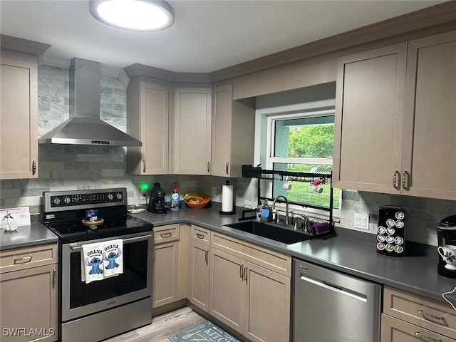 kitchen featuring appliances with stainless steel finishes, sink, wall chimney range hood, and backsplash