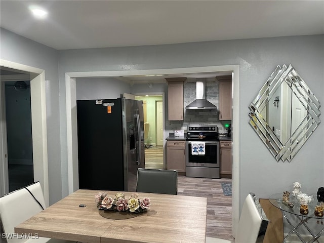 kitchen featuring appliances with stainless steel finishes, wall chimney exhaust hood, light hardwood / wood-style floors, and backsplash