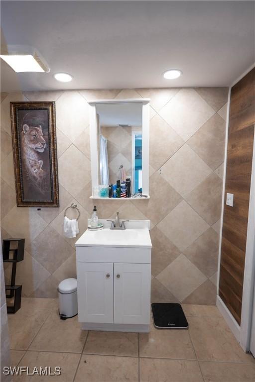 bathroom featuring tile patterned floors, vanity, recessed lighting, and tile walls