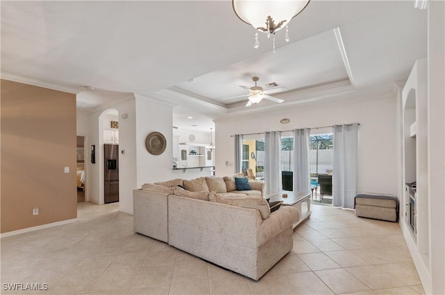 living room with light tile patterned floors, crown molding, a raised ceiling, and ceiling fan