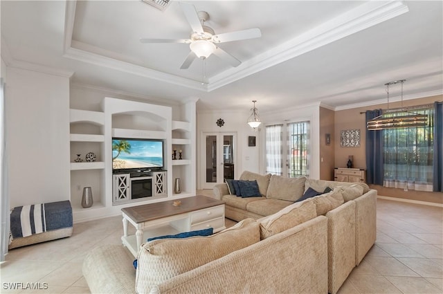 tiled living room featuring ornamental molding, built in shelves, ceiling fan, and a tray ceiling