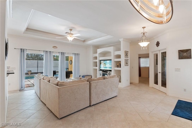 tiled living room featuring crown molding, a tray ceiling, french doors, and built in shelves