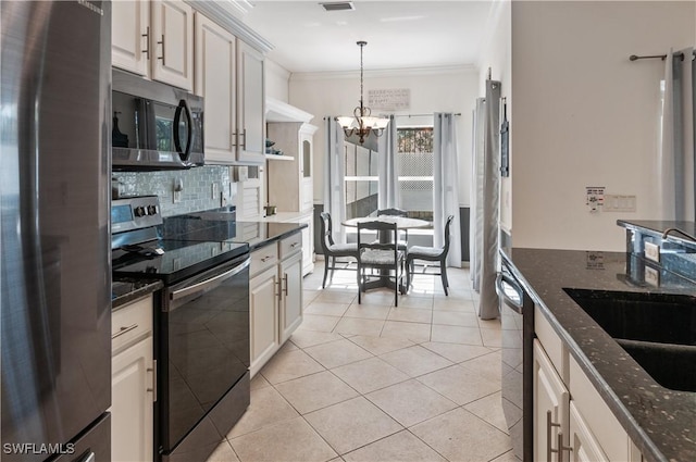 kitchen with appliances with stainless steel finishes, decorative light fixtures, sink, dark stone countertops, and light tile patterned floors