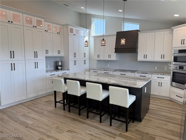 kitchen with hanging light fixtures, light stone countertops, white cabinets, and a kitchen island