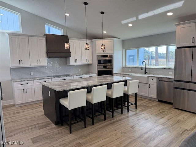 kitchen with pendant lighting, sink, appliances with stainless steel finishes, white cabinets, and a kitchen island