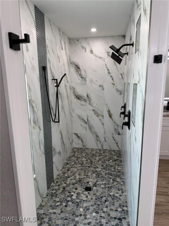 bathroom with hardwood / wood-style flooring and tiled shower