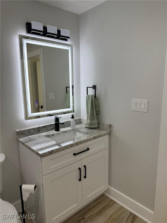 bathroom with vanity, toilet, and hardwood / wood-style floors