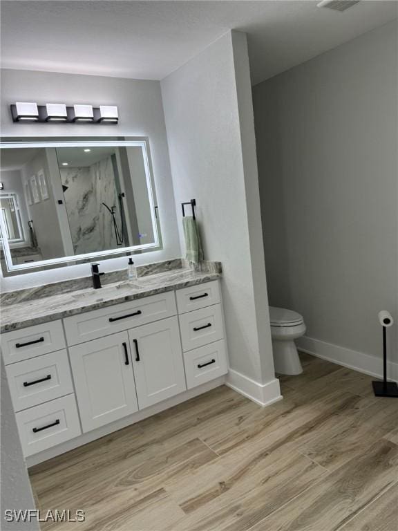 full bathroom with toilet, a marble finish shower, wood finished floors, and vanity