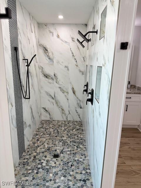 bathroom featuring vanity, a marble finish shower, and wood finished floors