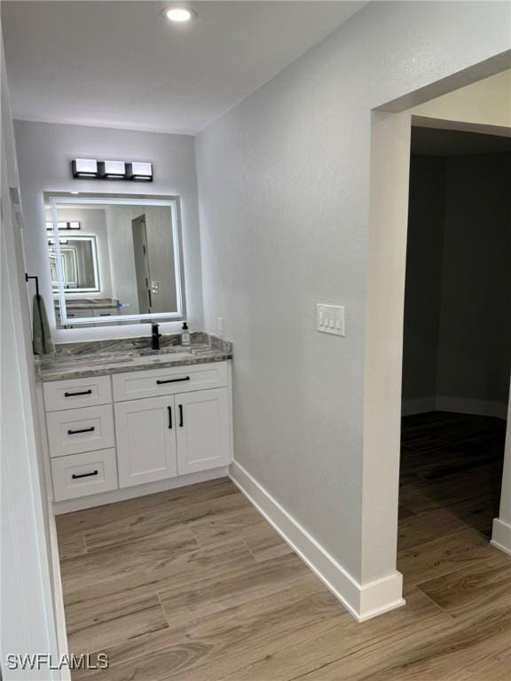 bathroom with recessed lighting, wood finished floors, vanity, and baseboards