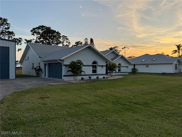 single story home featuring a garage, stucco siding, concrete driveway, and a yard