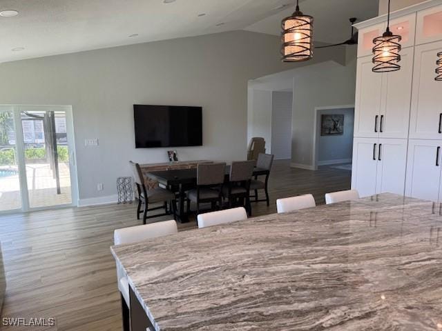 dining room featuring lofted ceiling, light wood-style flooring, and baseboards