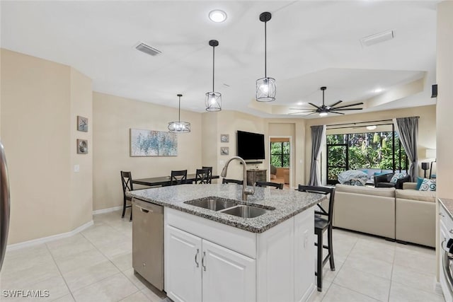 kitchen featuring an island with sink, light stone countertops, sink, stainless steel dishwasher, and white cabinets