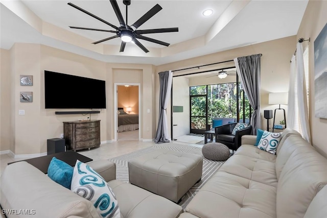 living room with a tray ceiling and ceiling fan