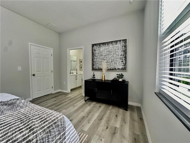 bedroom featuring ensuite bathroom and light hardwood / wood-style flooring