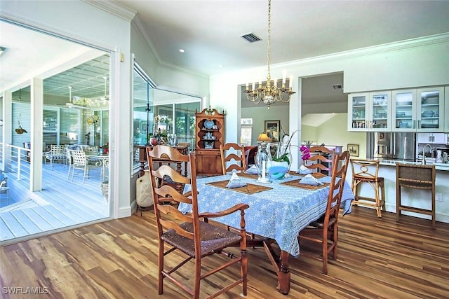 dining space with an inviting chandelier, crown molding, and wood-type flooring