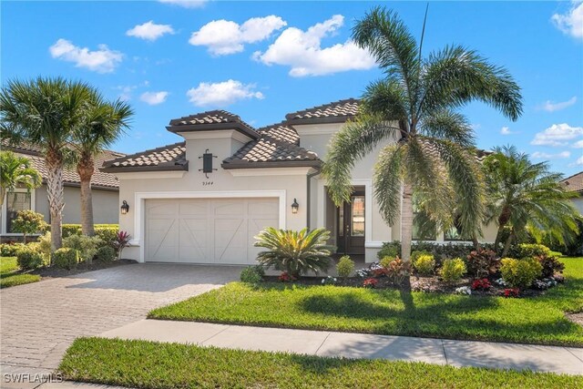 mediterranean / spanish house featuring a garage and a front lawn