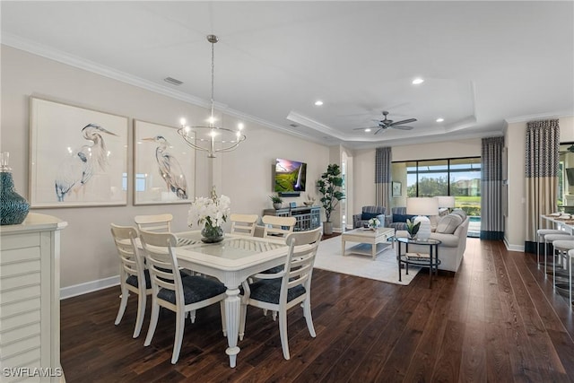 dining area featuring dark hardwood / wood-style flooring, crown molding, ceiling fan with notable chandelier, and a tray ceiling