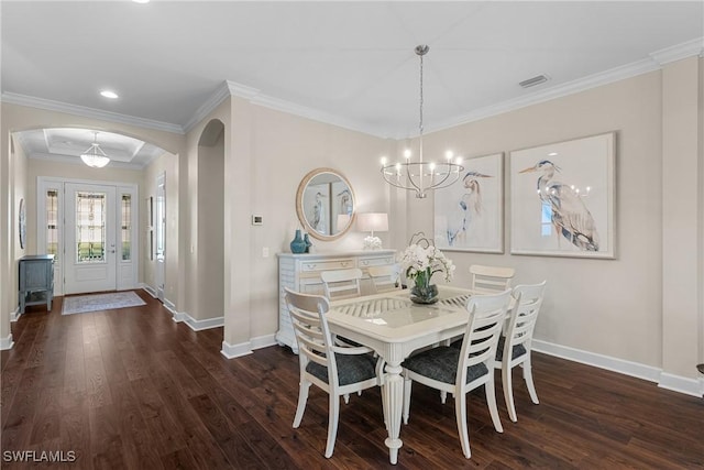 dining space with dark wood-type flooring, crown molding, and an inviting chandelier