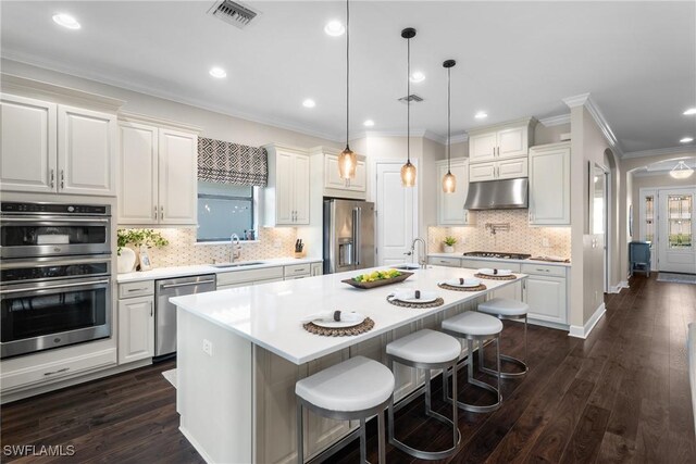 kitchen with stainless steel appliances, a kitchen bar, a center island with sink, and white cabinets