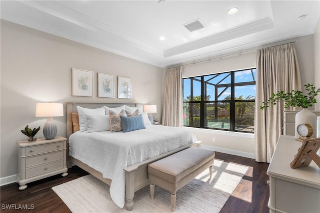 bedroom with crown molding, dark wood-type flooring, and a tray ceiling