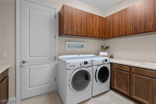 laundry room with cabinets, light tile patterned flooring, sink, and washing machine and clothes dryer