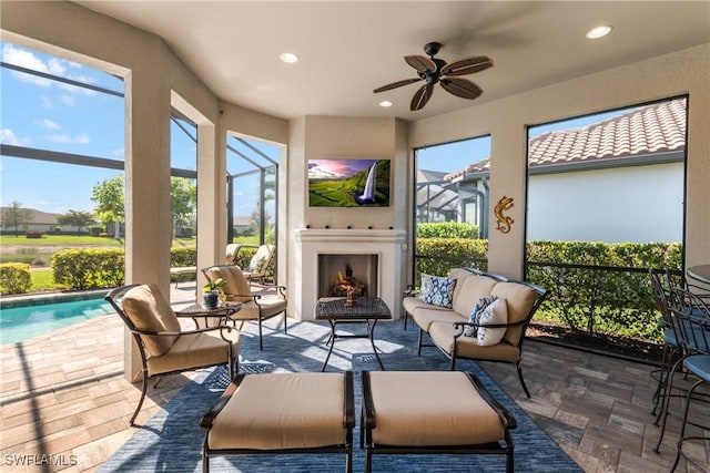 sunroom with a healthy amount of sunlight, ceiling fan, and an outdoor fireplace