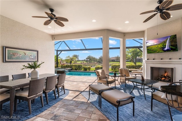 view of patio / terrace with ceiling fan, an outdoor fireplace, and glass enclosure