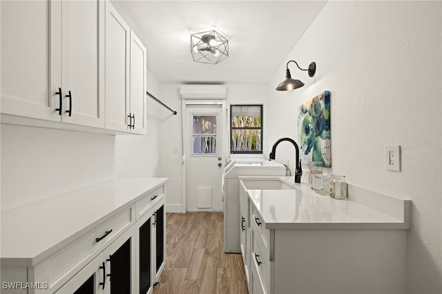 laundry area featuring cabinets, light hardwood / wood-style flooring, and washing machine and clothes dryer