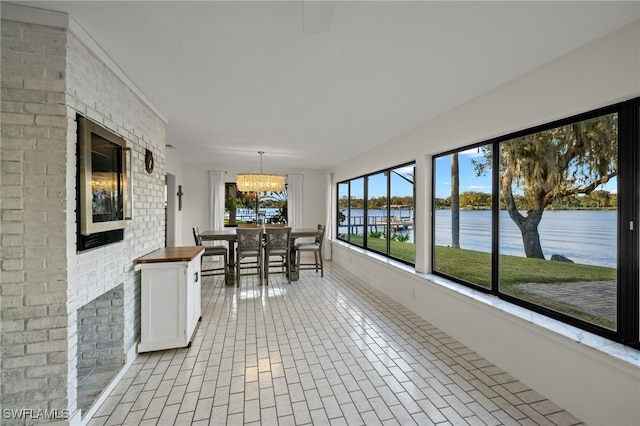 unfurnished sunroom featuring a water view and a chandelier