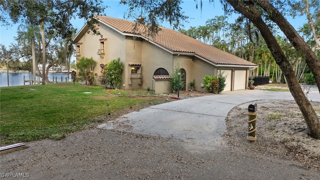 view of front of house featuring a garage, a front lawn, and a water view