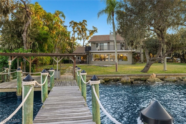 view of dock with a yard, a balcony, and a water view