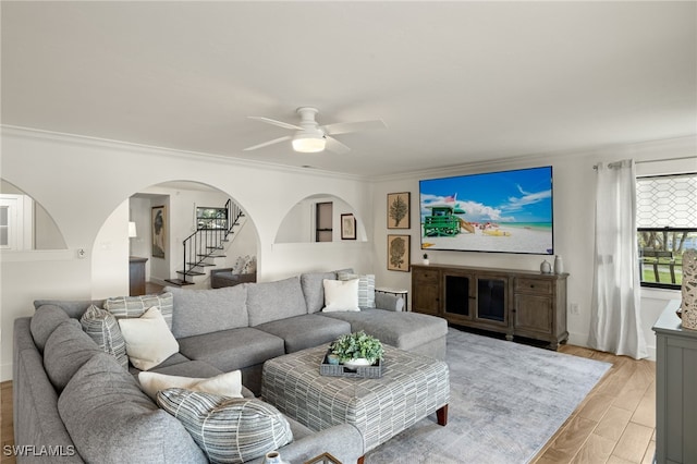 living room with ceiling fan, ornamental molding, and light wood-type flooring