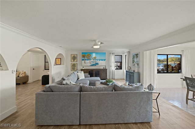 living room with ornamental molding, ceiling fan, and light wood-type flooring