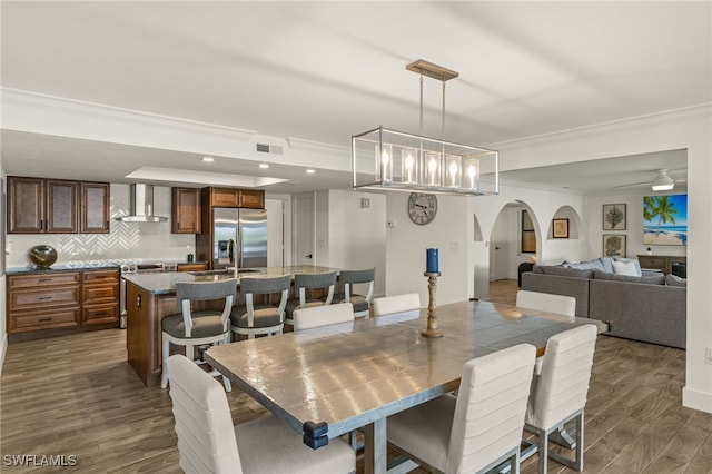 dining space featuring crown molding, sink, ceiling fan with notable chandelier, and dark hardwood / wood-style flooring