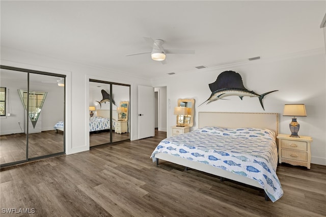 bedroom featuring crown molding, ceiling fan, dark hardwood / wood-style floors, and two closets